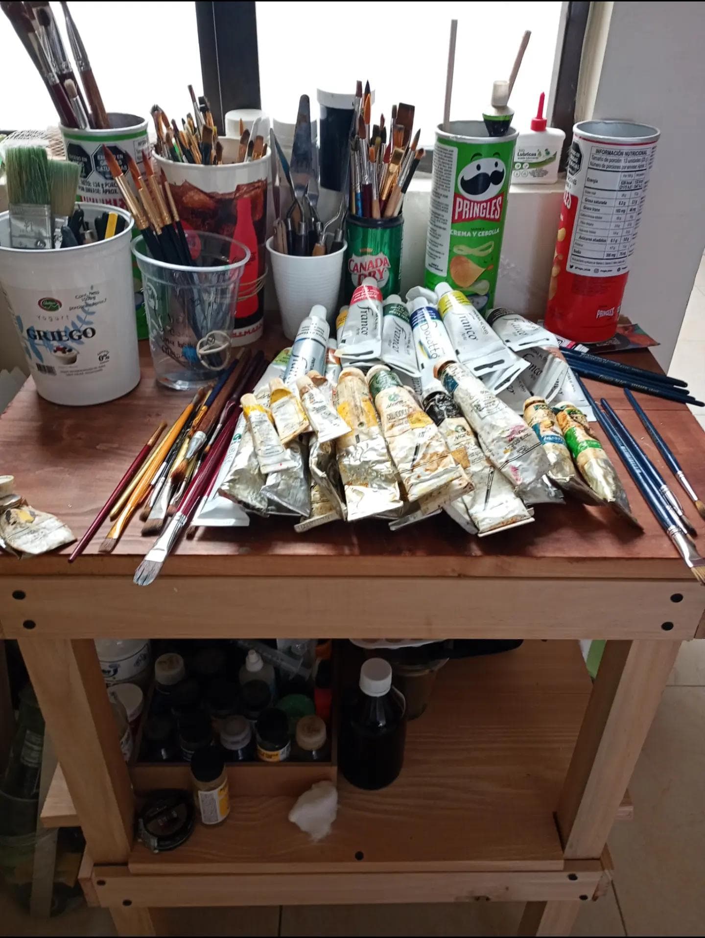 Fotografía de pinceles y tubos de pintura sobre una mesa.